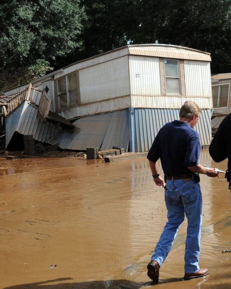 Two men walk through floodwater past damaged homes in Austell, Georgia