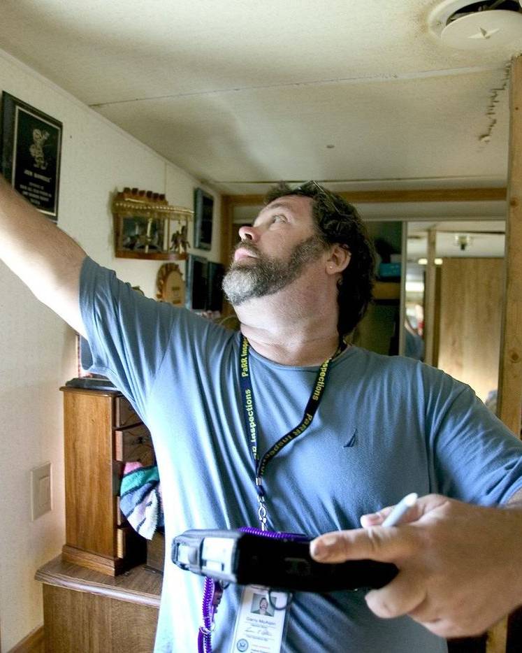 An inspector checks a damaged ceiling inside a home