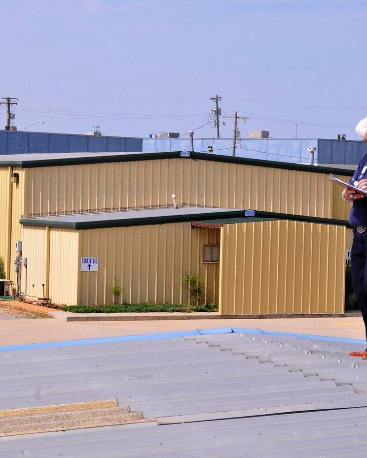 An inspector takes notes on a damaged commercial roof