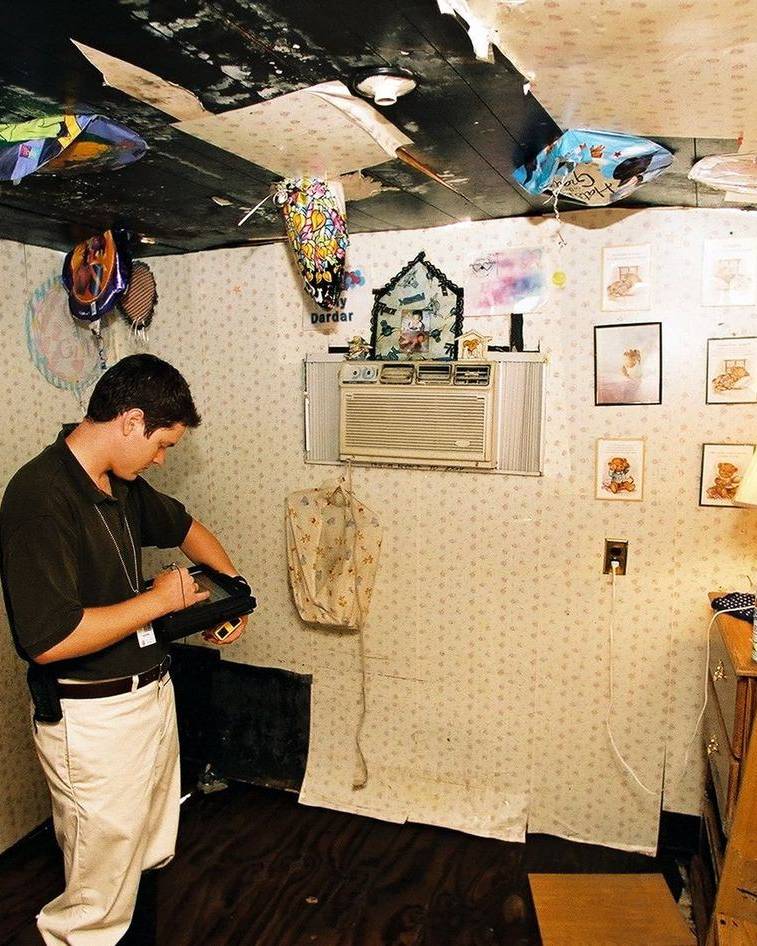 An inspector documents damage inside a bedroom