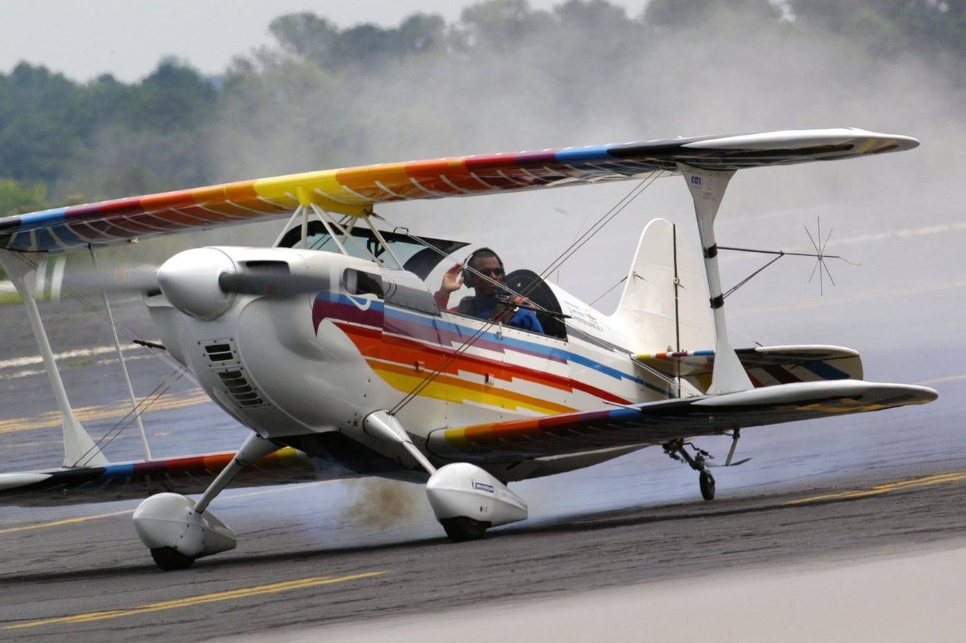An aerobatic biplane taxiing on a runway