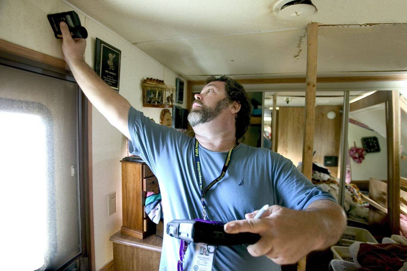An inspector checks a damaged ceiling inside a home