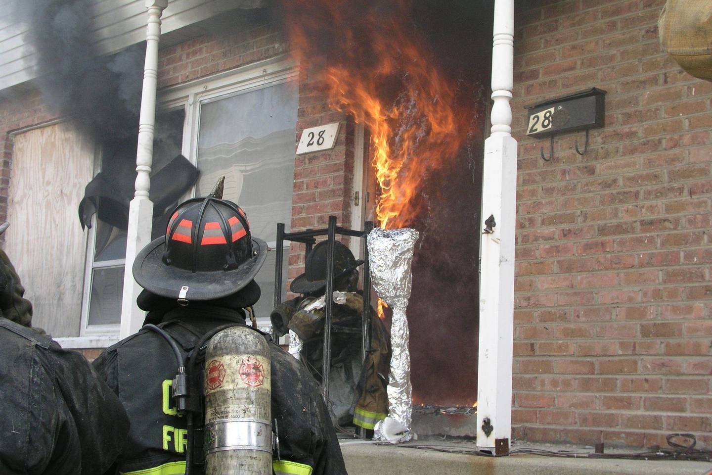 A firefighter at the door of a burning townhouse